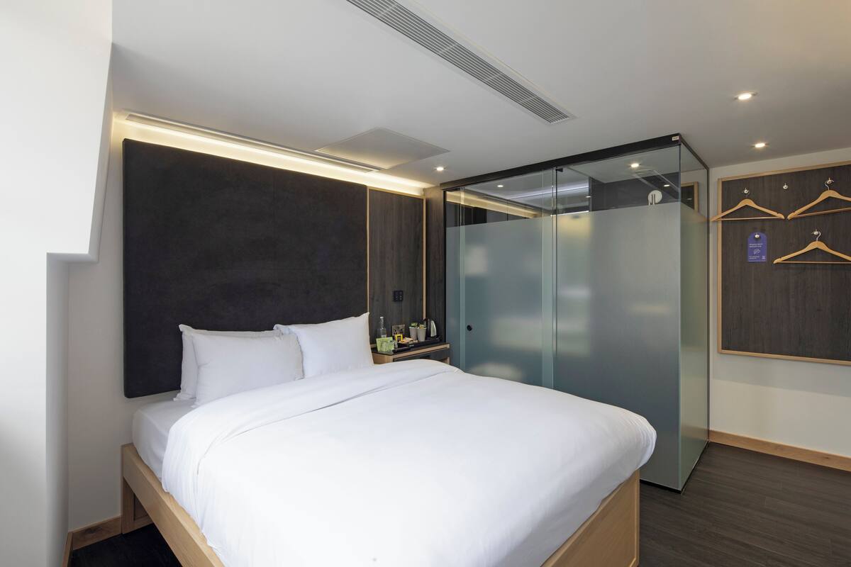 A modern hotel room with a large bed, a wardrobe, and a mirror.