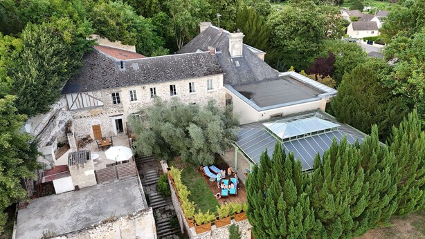 Una casa de piedra con un jardín amplio, un porche cubierto y un techo con paneles solares.