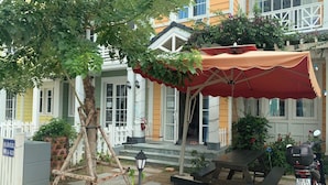 A house with a porch, a table, and a motorcycle parked outside. - Deluxe 3 Br Happy House - Novaworld PT (Tien Thanh)