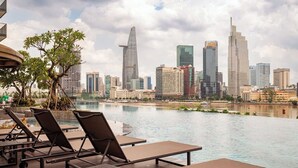 A poolside area with lounge chairs and a city skyline in the background. - Landmark 81 Magical Tower Apartment (Ho Chi Minh City)