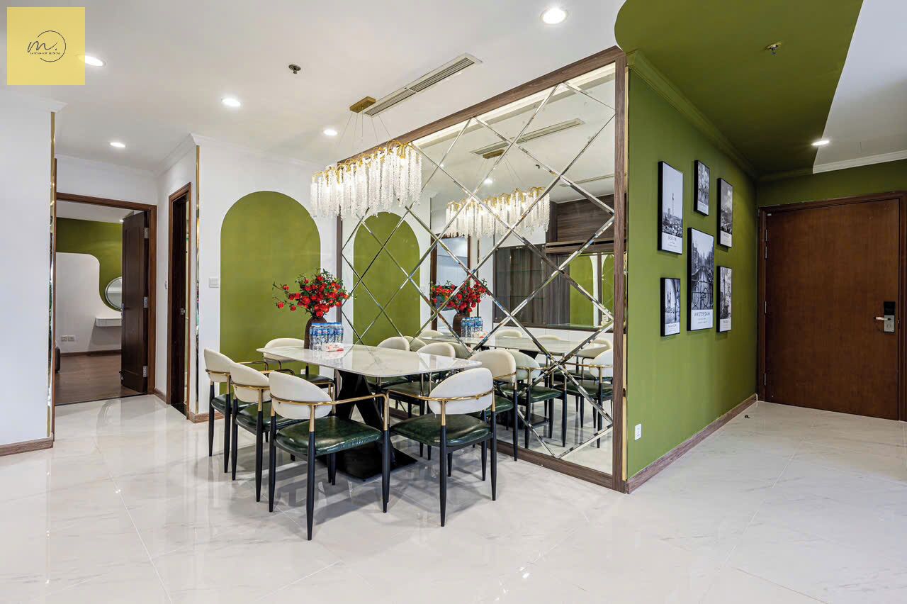 Un comedor con una mesa grande y sillas, paredes verdes y cuadros en la pared.