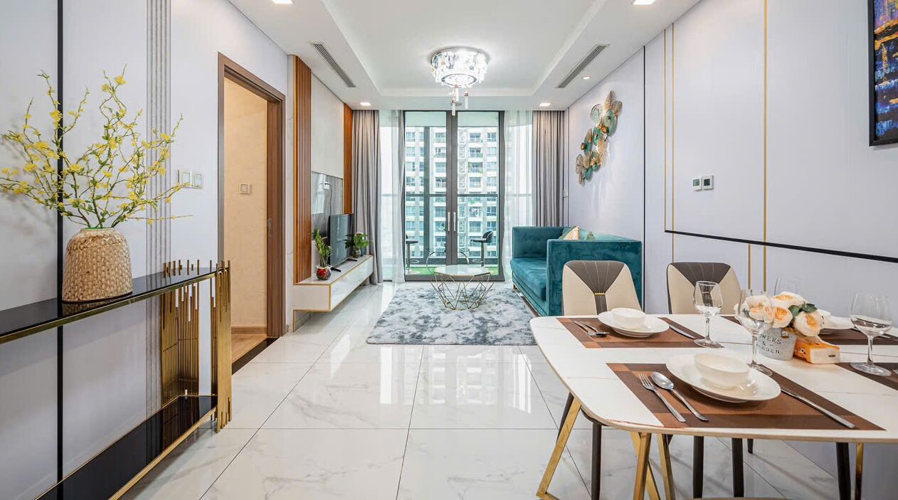 A modern living room with a sofa, dining table set, and a view of a balcony.