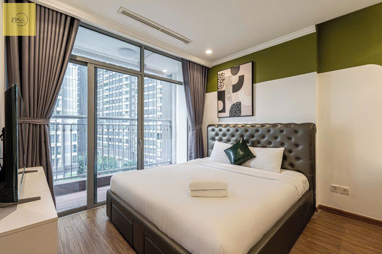 Habitación de hotel con una cama grande, televisión y vistas a la ciudad a través de un ventanal.