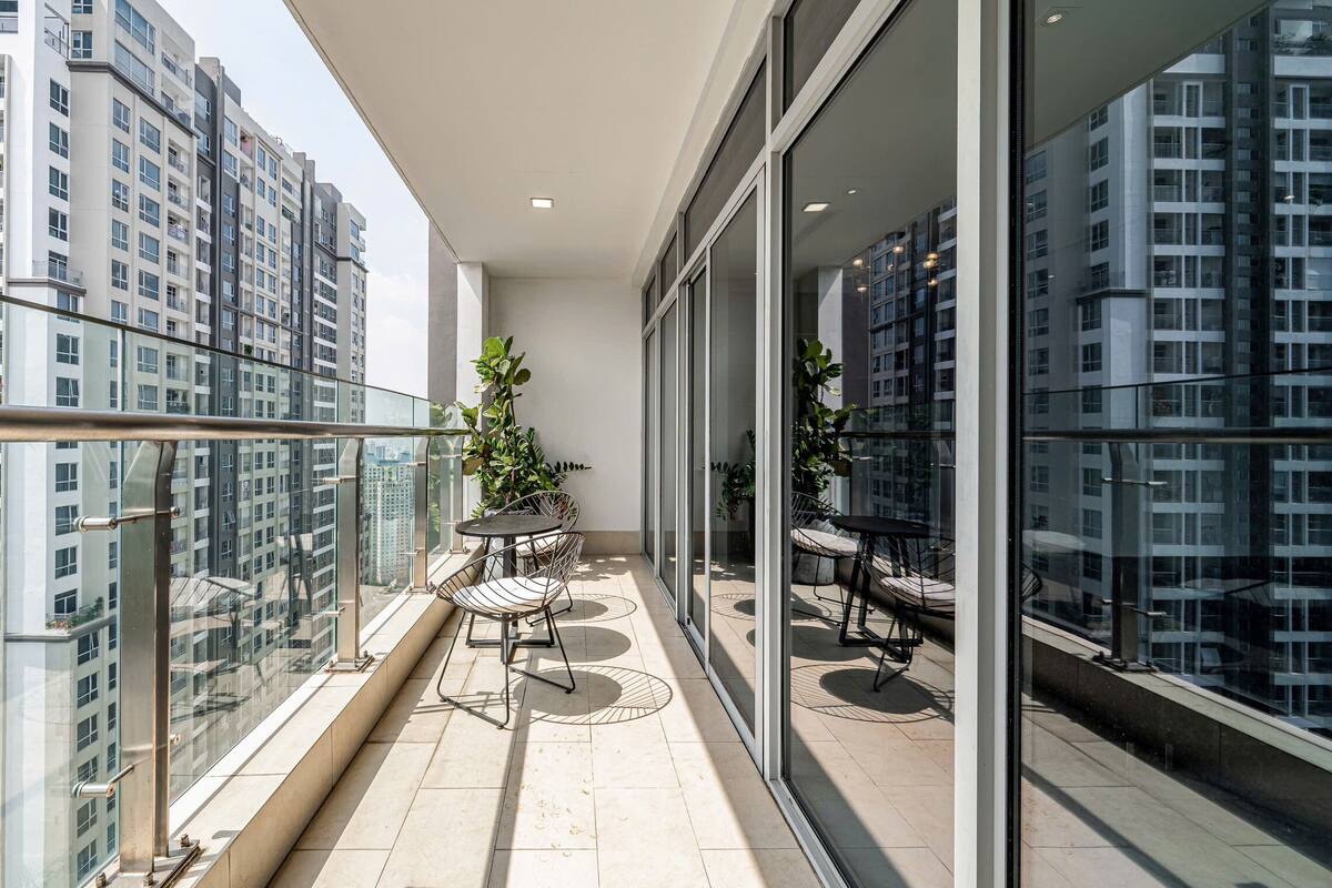 A modern balcony with glass railings, a round table, and two chairs.