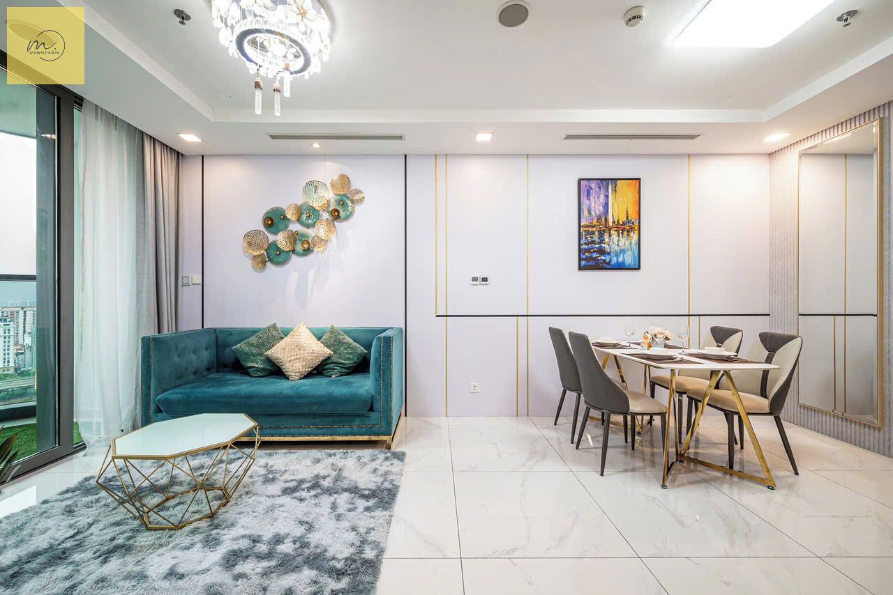 A modern living room with a teal sofa, a dining table with chairs, and a chandelier.