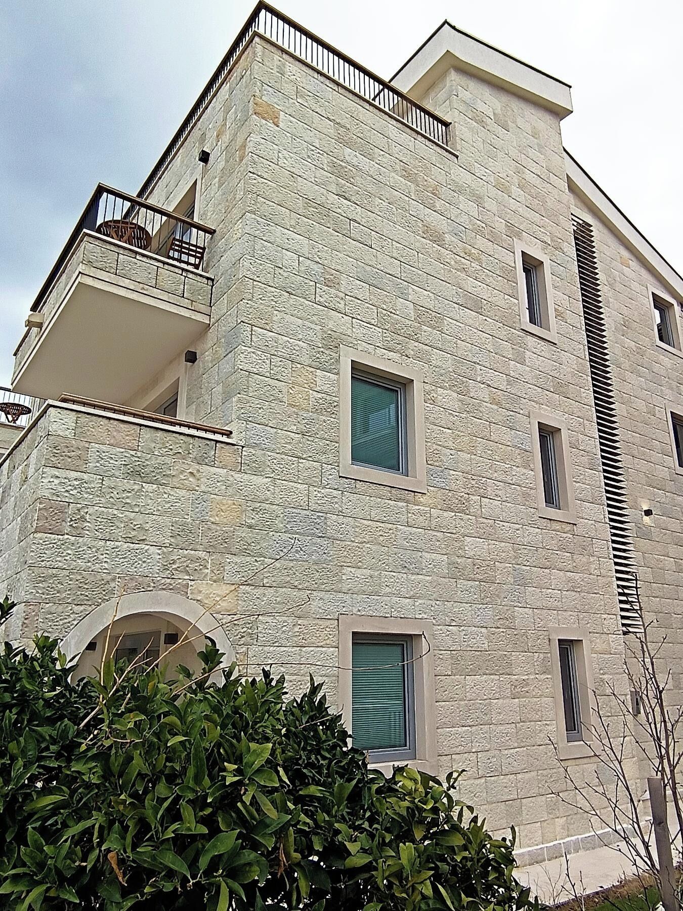 Um edifício com várias andares, fachada de pedra, varandas e janelas.