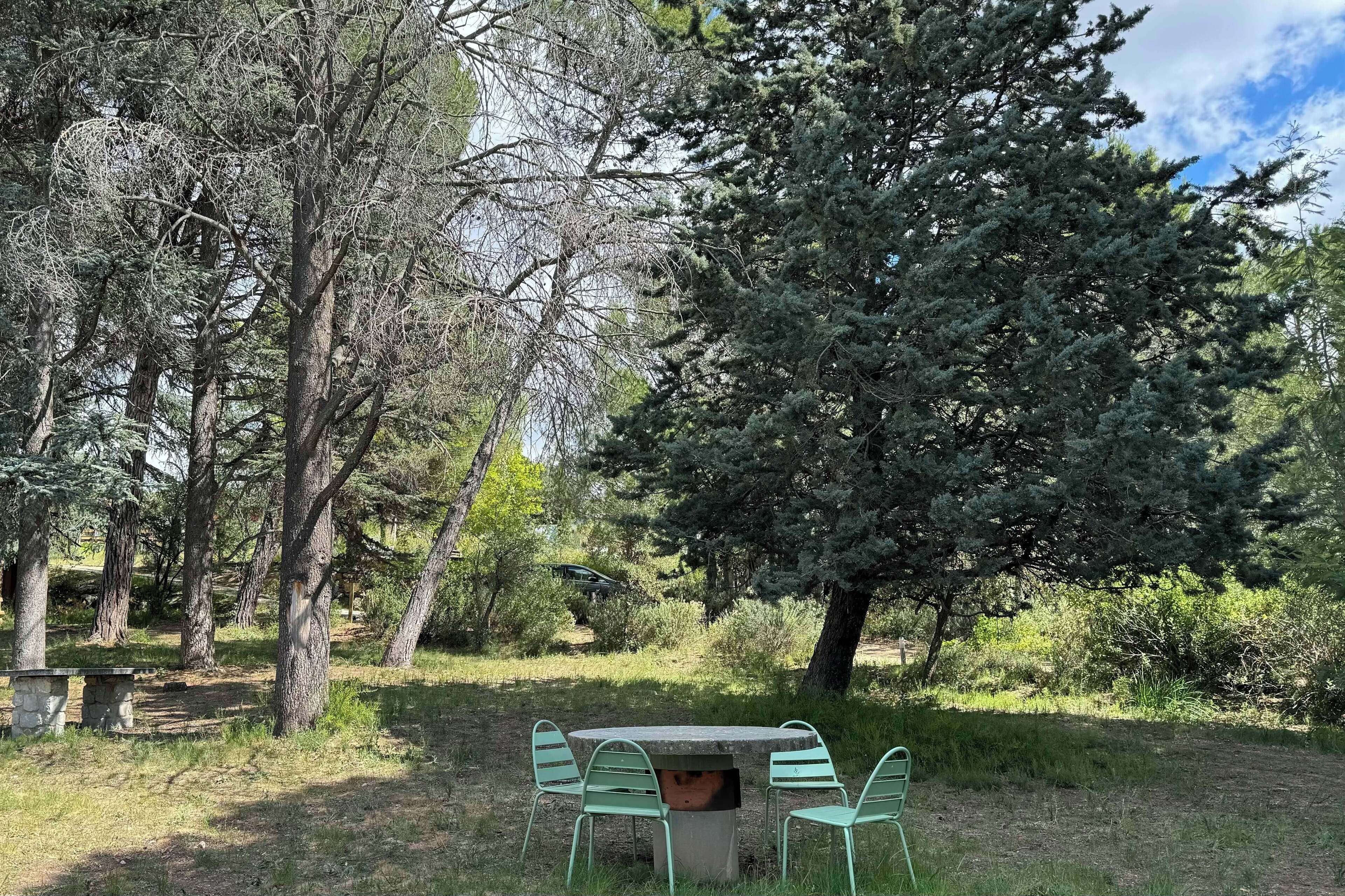A picnic table with chairs in a wooded area.