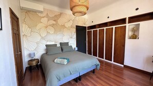A bedroom with a large bed, a wooden wardrobe, and a wall with a floral pattern. - Domaine de l'Aven (Villeneuve-Minervois)