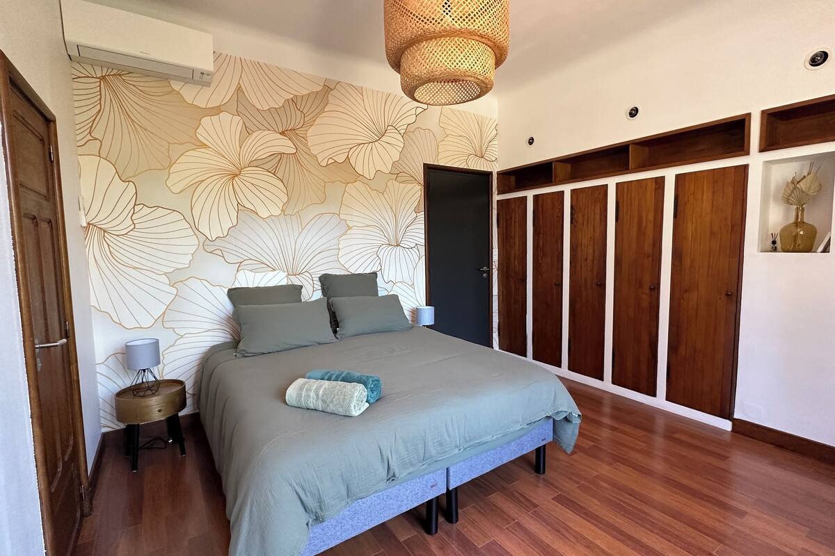 Un dormitorio con una cama grande, un armario de madera y una pared con estampado floral.