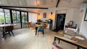 A dining area with a large window, a kitchen counter, and a dining table with chairs. - Domaine de l'Aven (Villeneuve-Minervois)