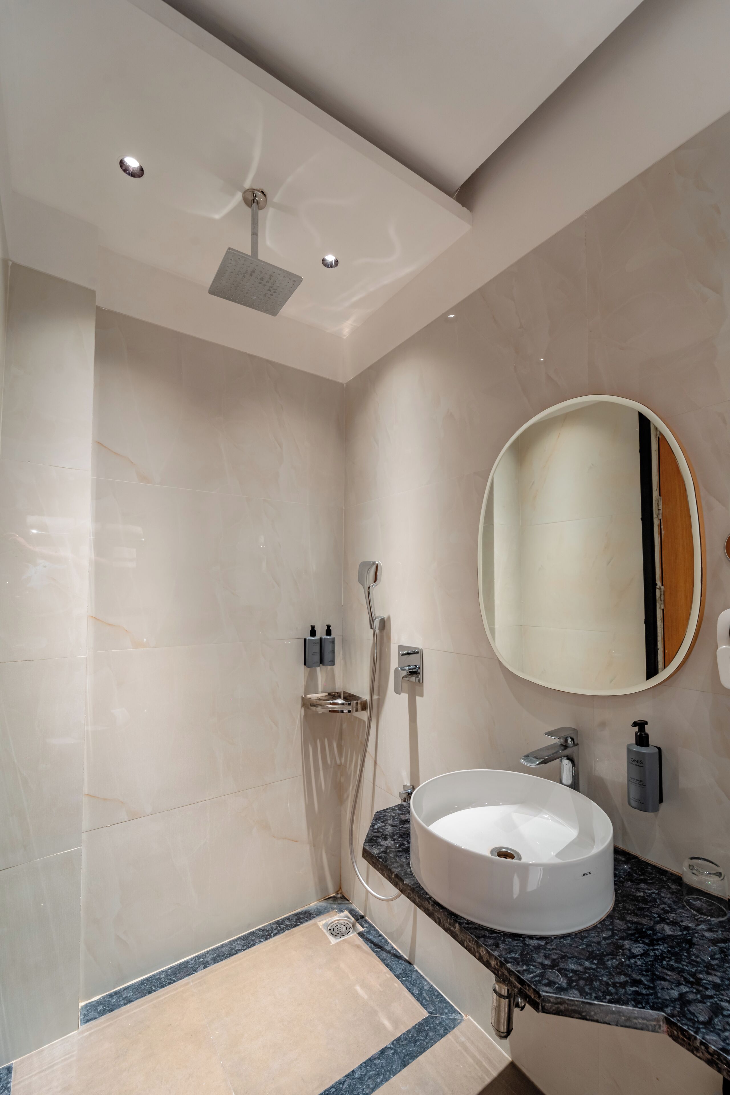 A modern bathroom with a large mirror, a round sink, and a shower.