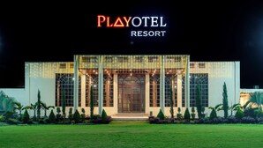 Ein Playotel Resort Gebäude bei Nacht mit beleuchteter Beschilderung, großen Fenstern und einem gut beleuchteten Eingang.