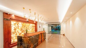 Ein moderner Empfangsbereich mit Marmorplatte, einer dekorativen Wand und einer Glastür zu einem Innenhof.