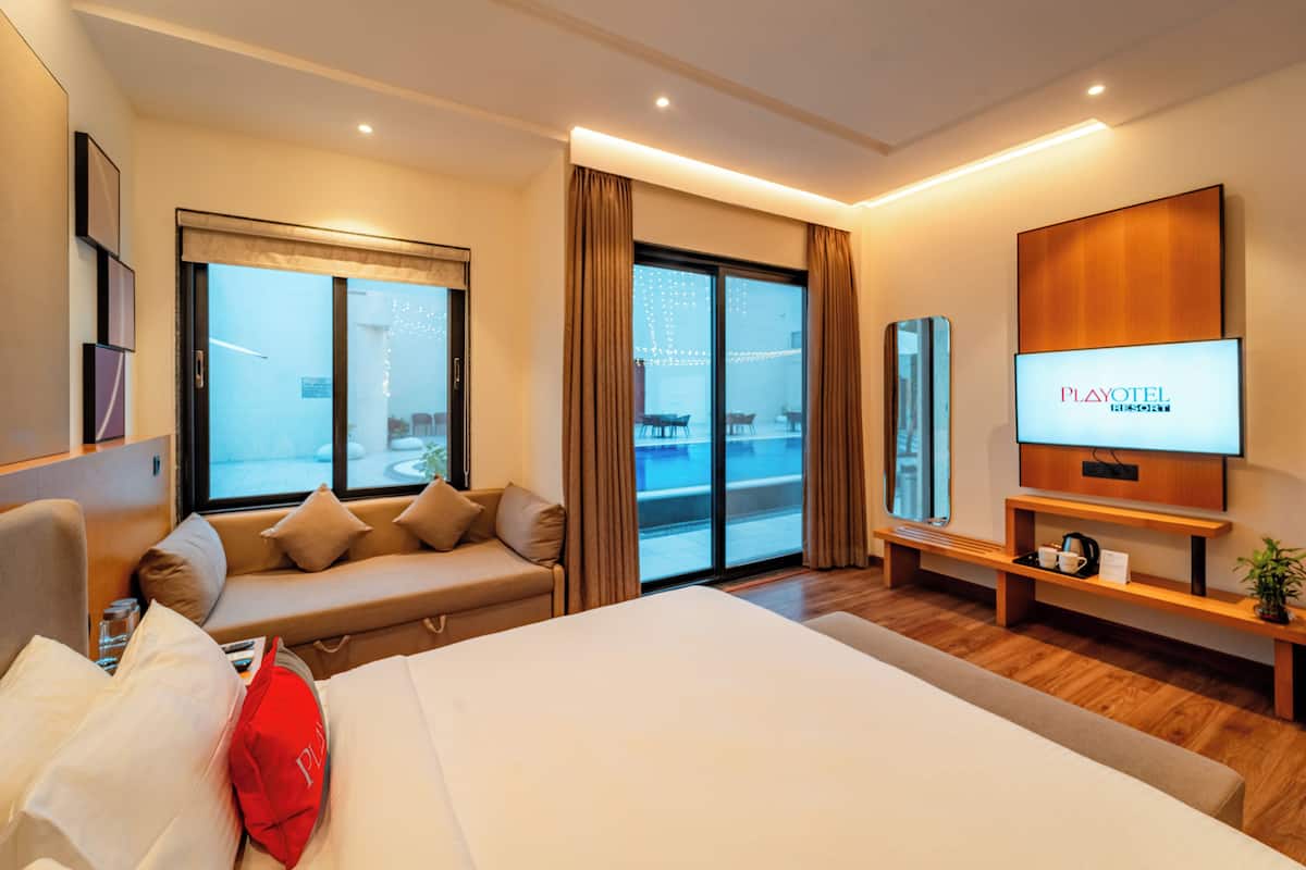 Una habitación de hotel moderna con una cama grande, un sofá, un televisor y un balcón con vistas.