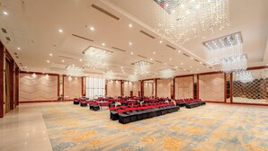 A spacious banquet hall with rows of tables and chairs, large chandeliers, and a patterned carpet. - Playotel Resort Indore (Indore)