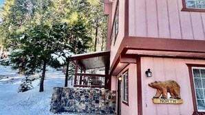 Un bâtiment en bois avec une entrée surmontée d’un mur en pierre, un panneau représentant un ours et un porche abrité.