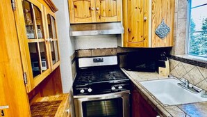 Une cuisine de taille réduite, dotée de meubles en bois, d’une cuisinière en acier inoxydable et d’un évier.