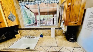 Une cuisine équipée d’un évier, d’une machine à café et d’une fenêtre donnant sur l’extérieur.