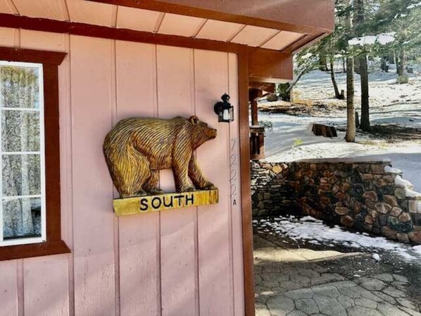 Una cabaña de madera con un letrero con forma de oso que indica 'SOUTH' en la puerta.