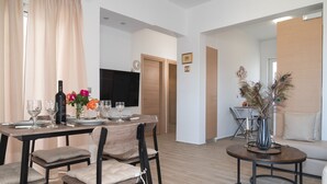A dining area with a wooden table set for four, a sofa, and a decorative vase.