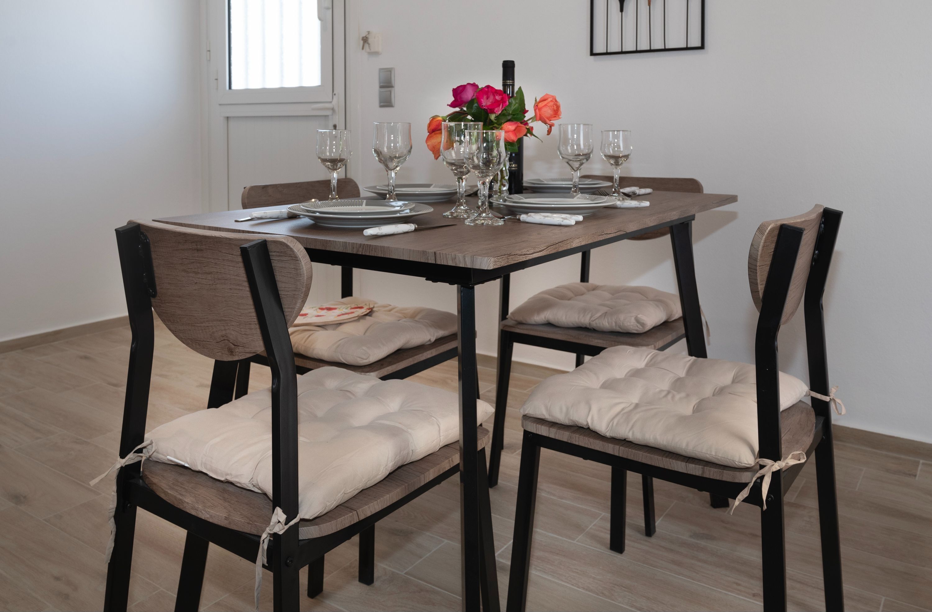 Une table à manger dressée avec des assiettes, des verres et un vase de fleurs.