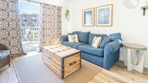 Un salon avec un canapé bleu, une commode en bois et une petite table ronde.