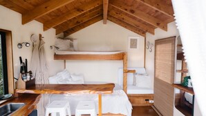A compact, rustic cabin with a loft-style sleeping area, a wooden dining table, and a kitchenette.