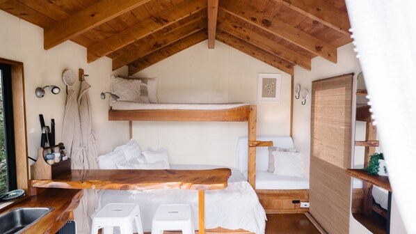 A compact, rustic cabin with a loft-style sleeping area, a wooden dining table, and a kitchenette.