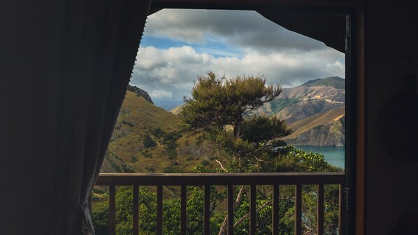A balcony with a view of a mountainous landscape and a body of water.