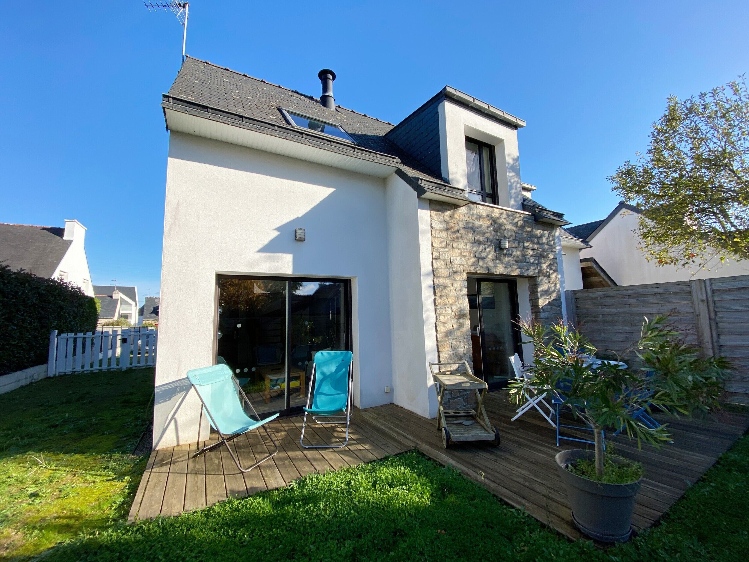 A modern house with a large deck, a sliding glass door, and a chimney.