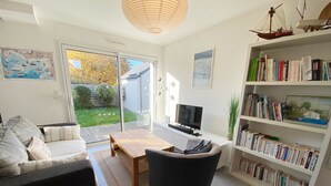 A modern living room with a sofa, a coffee table, a TV, and a bookshelf filled with books. - MASSALINE - Holiday home between town and beaches, Carnac - K38 (Carnac)