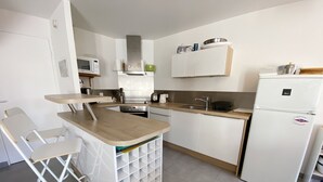 A compact kitchen with a wooden countertop, white cabinets, a built-in oven, a microwave, and a refrigerator. - MASSALINE - Holiday home between town and beaches, Carnac - K38 (Carnac)