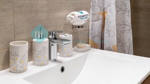 A bathroom sink with a towel rack, a soap dish, and two decorative mugs. - Bloomfields Stylish 1BR In Oasis Masdar City (Abu Dabi)