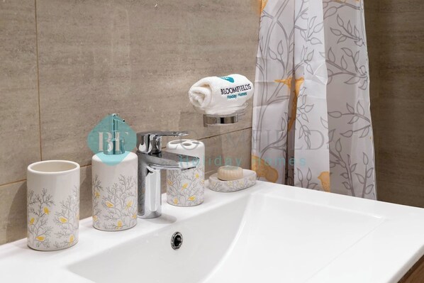 A bathroom sink with a towel rack, a soap dish, and two decorative mugs.