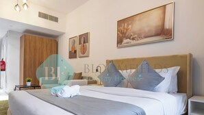 Een hotelkamer met een groot bed, een houten garderobe, een nachtkastje met een lamp en een schilderij aan de muur.