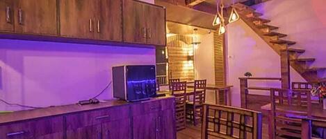 A rustic kitchen with wooden cabinets, a dining area with a wooden table, and a staircase leading to another level.