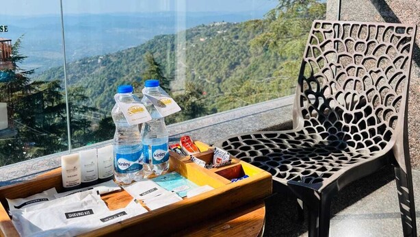 A wooden tray with toiletries and a shaving kit on a balcony with a view of a mountainous landscape. - THE SIDDHARTHA (Dharamshala)