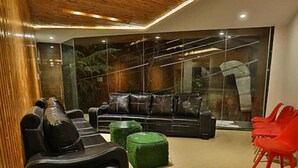 A modern living room with a sofa, ottomans, and red chairs. - THE SIDDHARTHA (Dharamshala)