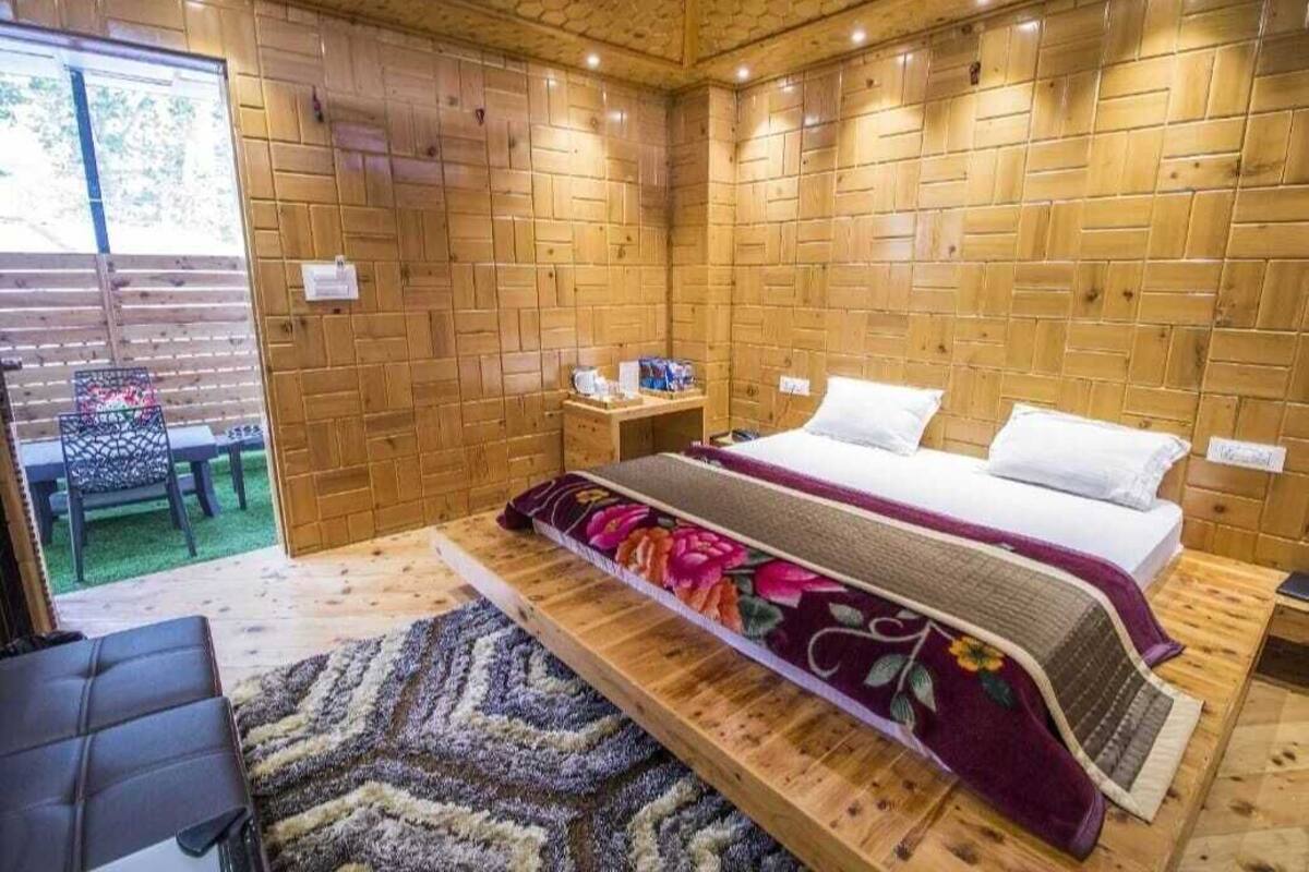 A wooden-paneled room with a bed, a small table, and a chair.