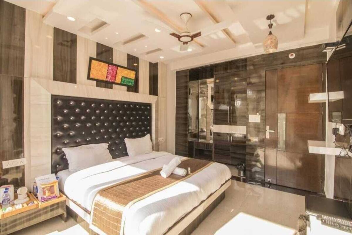 A modern hotel room with a large bed, a glass-enclosed shower, and a ceiling fan.