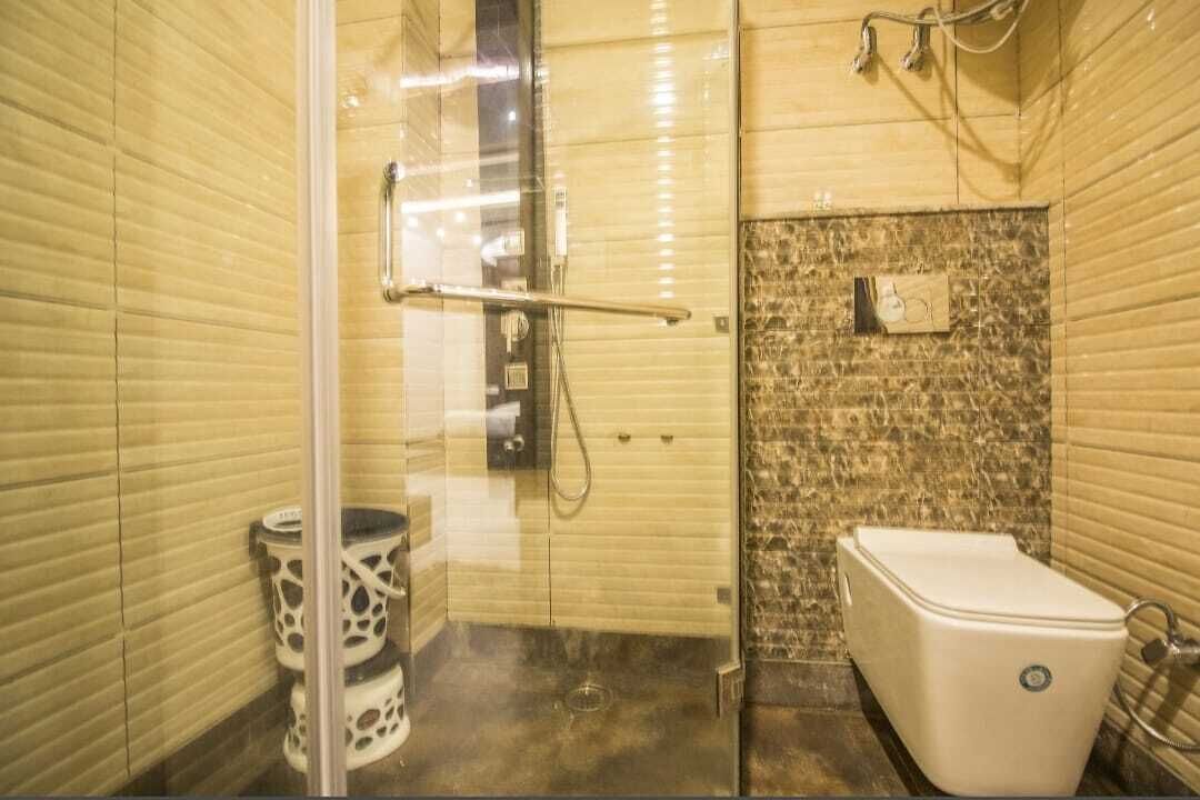Un baño con cabina de ducha de vidrio, inodoro y lavamanos.