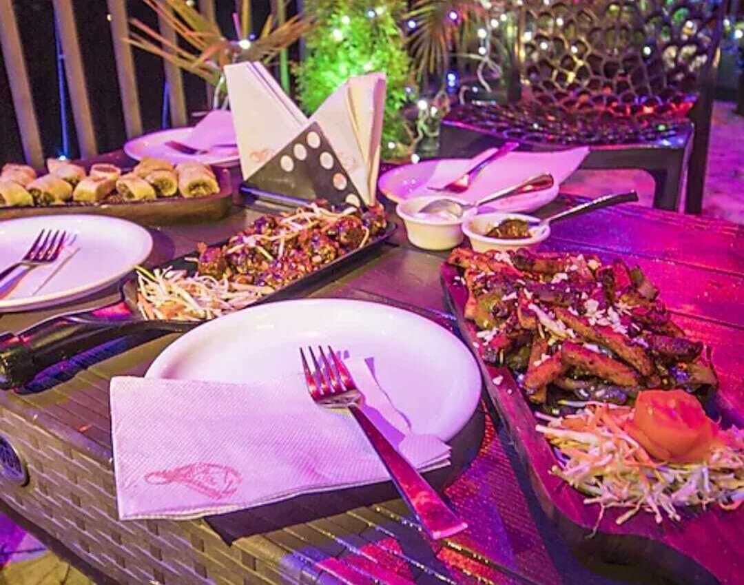 Mesa puesta con platos, cubiertos y diferentes platos, probablemente en un restaurante o zona de comedor.