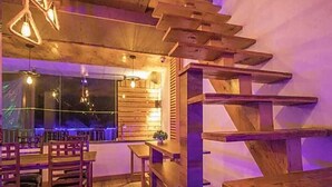 A wooden interior with a staircase, tables, and chairs. - THE SIDDHARTHA (Dharamshala)