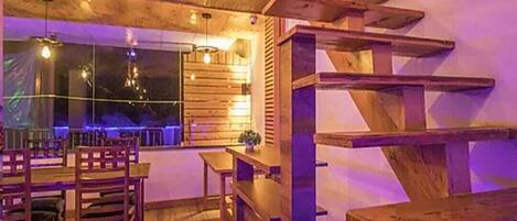 A wooden interior with a staircase, tables, and chairs.