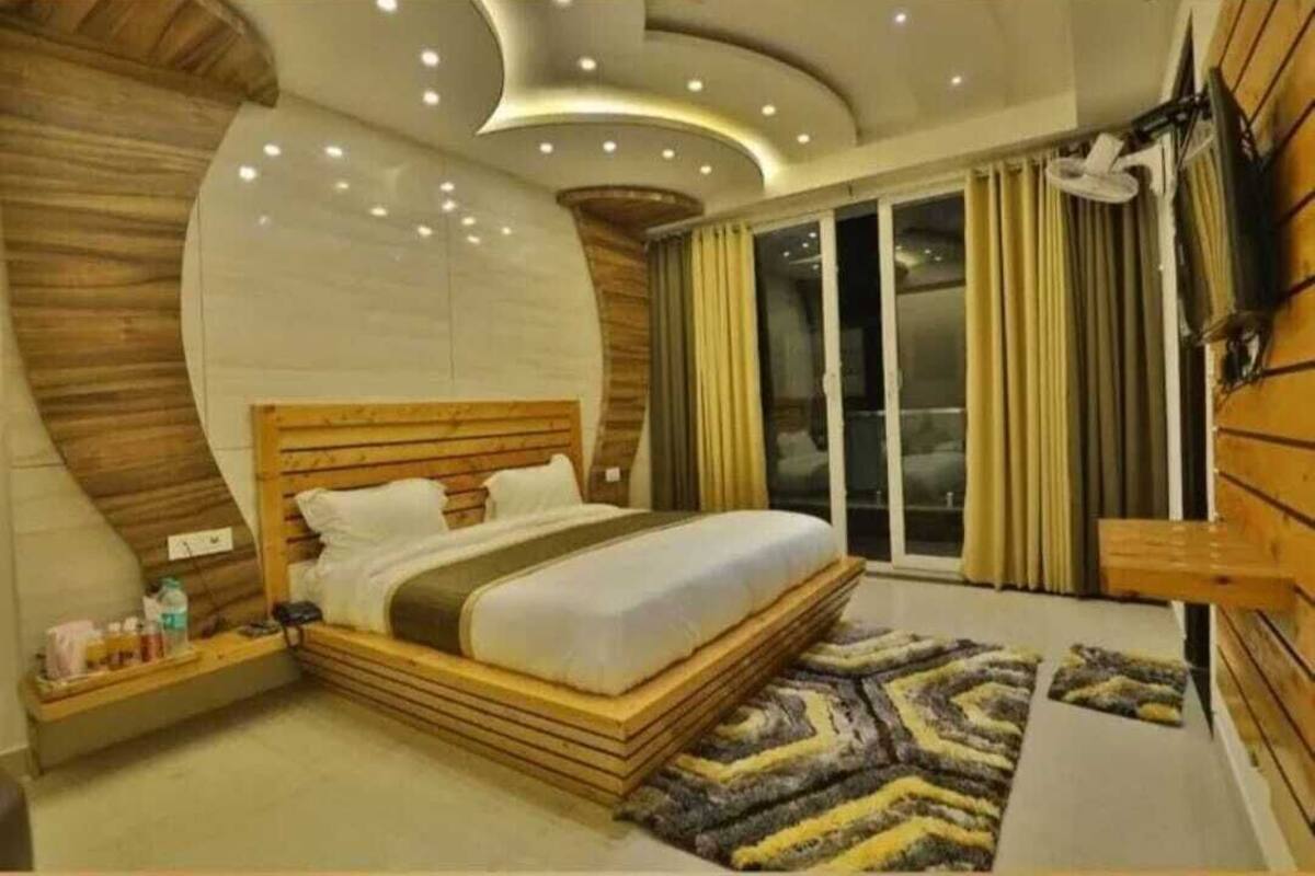 A modern bedroom with a curved ceiling, a wooden headboard, a large bed, a bedside table, and a view of the outside through a sliding glass door.