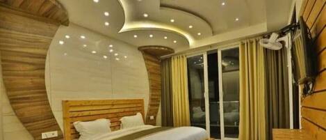 Ein modernes Schlafzimmer mit gewölbter Decke, einem Holz-Kopfteil, einem großen Bett, einem Nachttisch und Blick ins Freie durch eine Schiebeglastür.