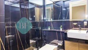 Un bagno moderno con una parete in marmo nero, un lavandino bianco e uno specchio sopra.