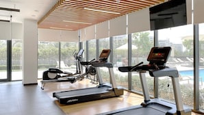 Une salle de sport équipée de tapis de course, de vélos d’appartement et d’un appareil d’aviron.