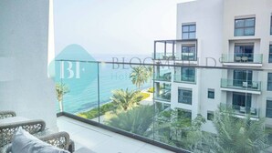A balcony with a glass railing overlooking a coastal view, part of a modern hotel building.