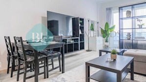 Un salon moderne comprenant un coin repas, un canapé, une table basse et une grande fenêtre avec des rideaux.